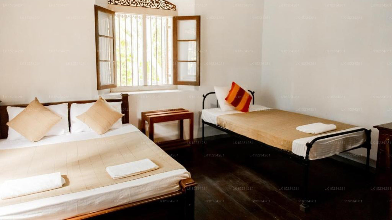 Two beds in a room with a window and wooden furniture.