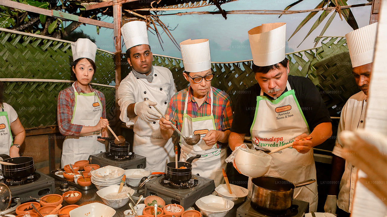 Participants wearing chef hats and aprons cooking traditional dishes during a guided Sri Lankan cooking class.